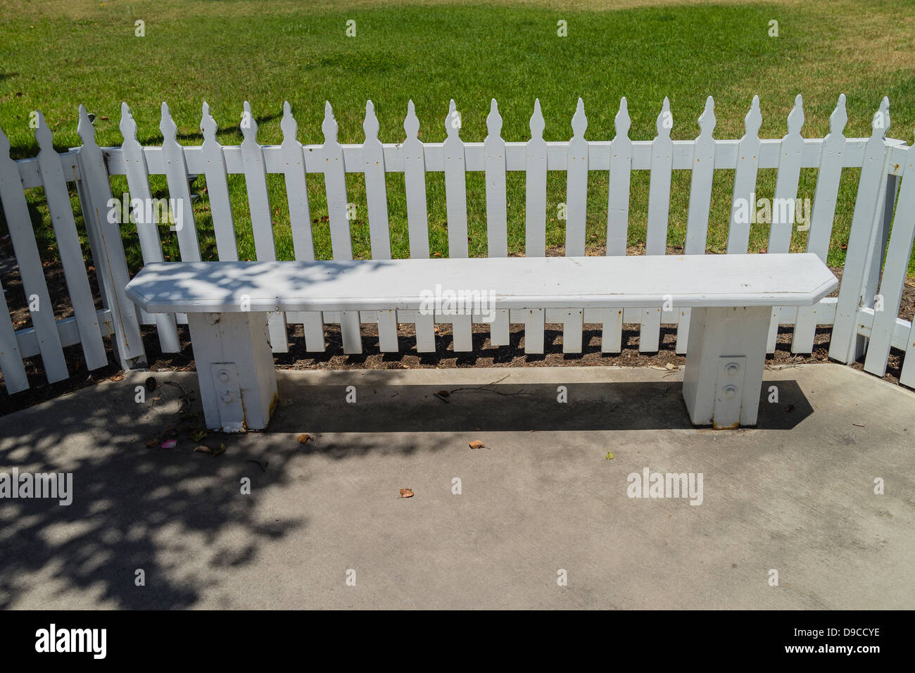 A white wooden bench located in front of an old style white picket ...