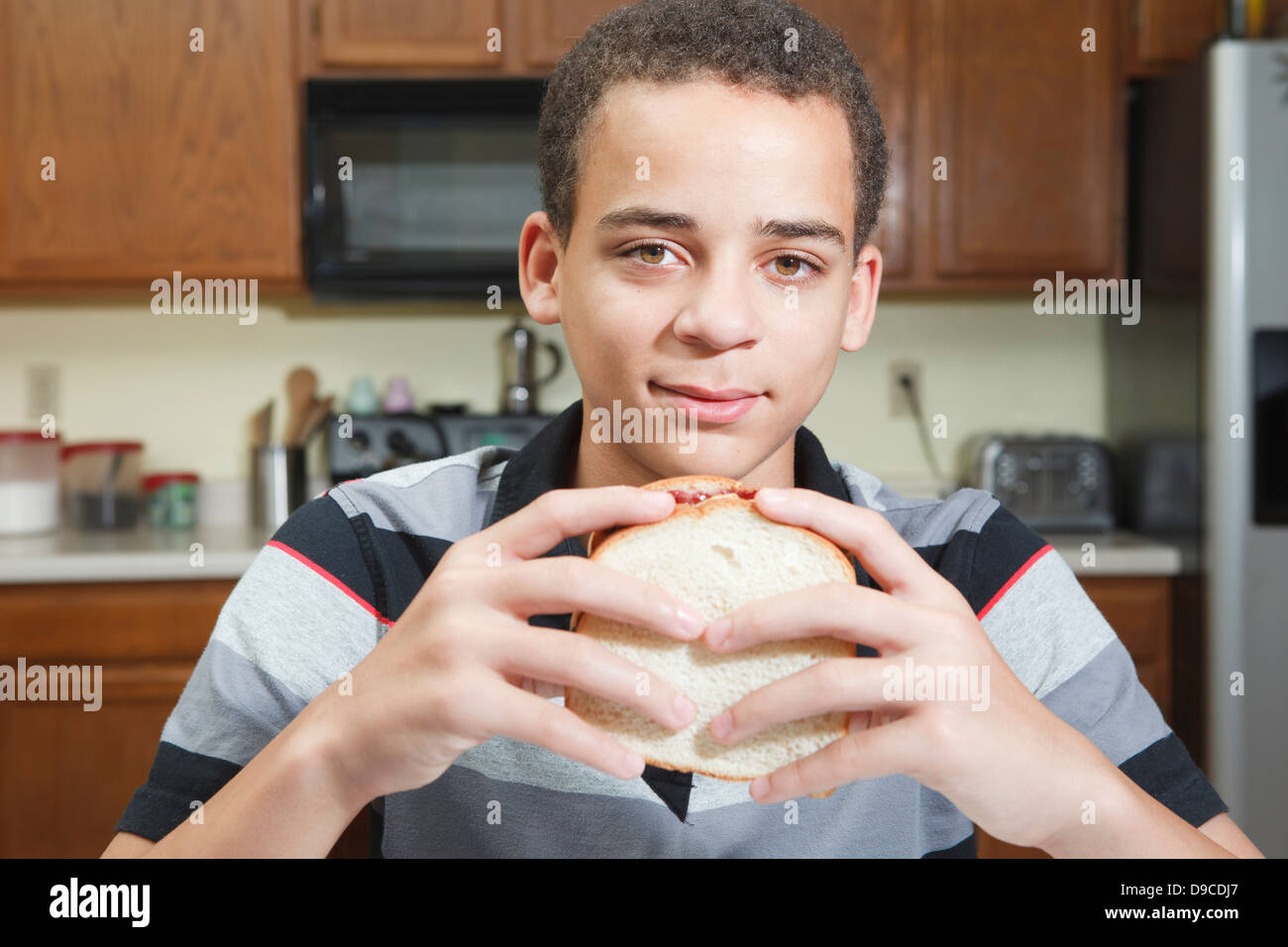 Handsome young mixed ethnic teenage boy sitting in kitchen at table