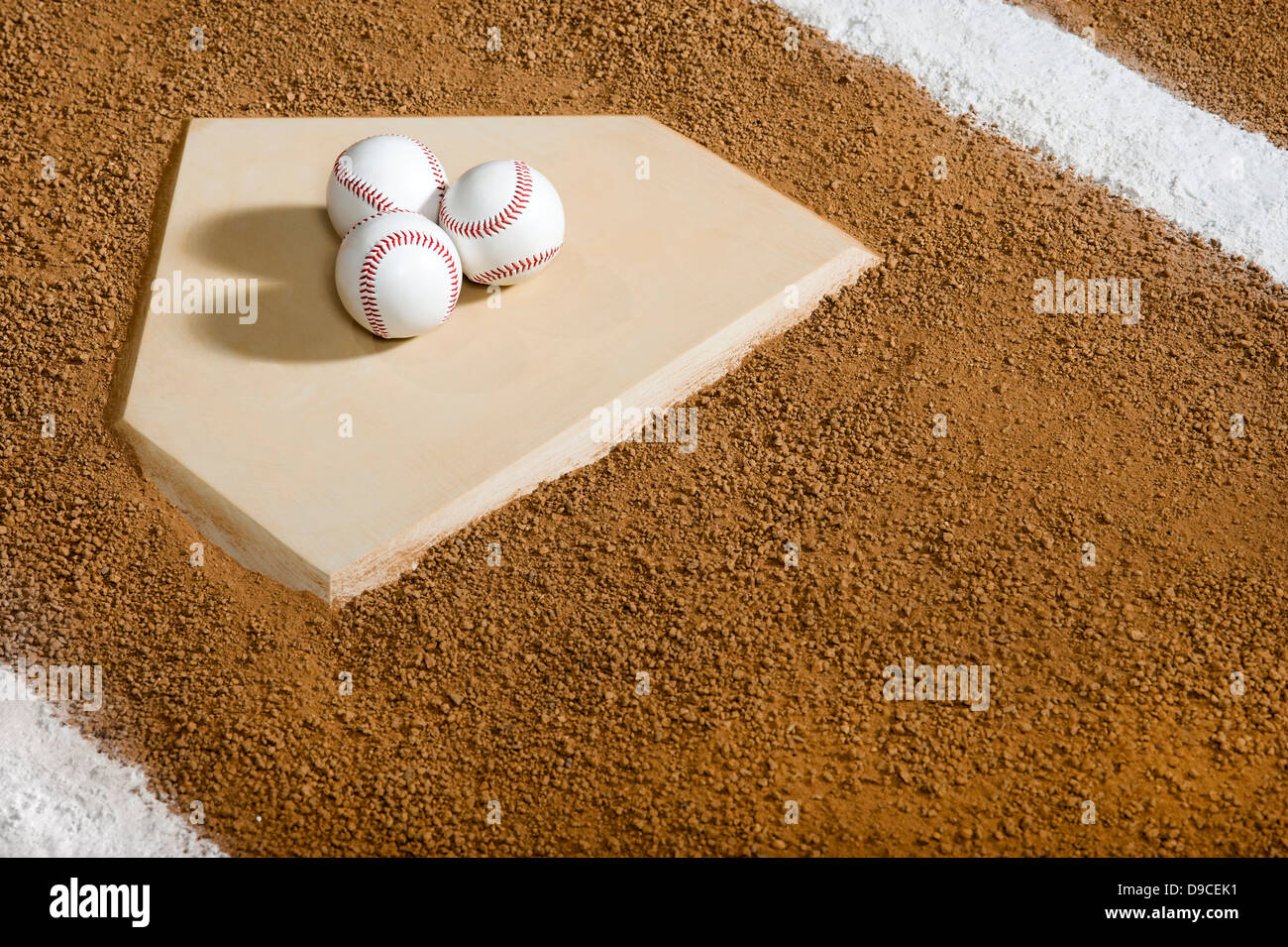 Three new Baseballs sitting on Home Plate with the chalk lines of the batter's box Stock Photo