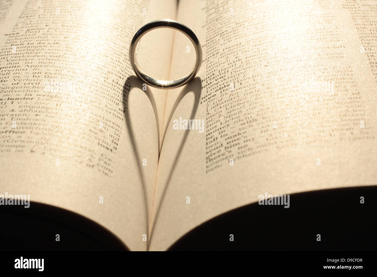 Heart shadow from wedding ring on book Stock Photo
