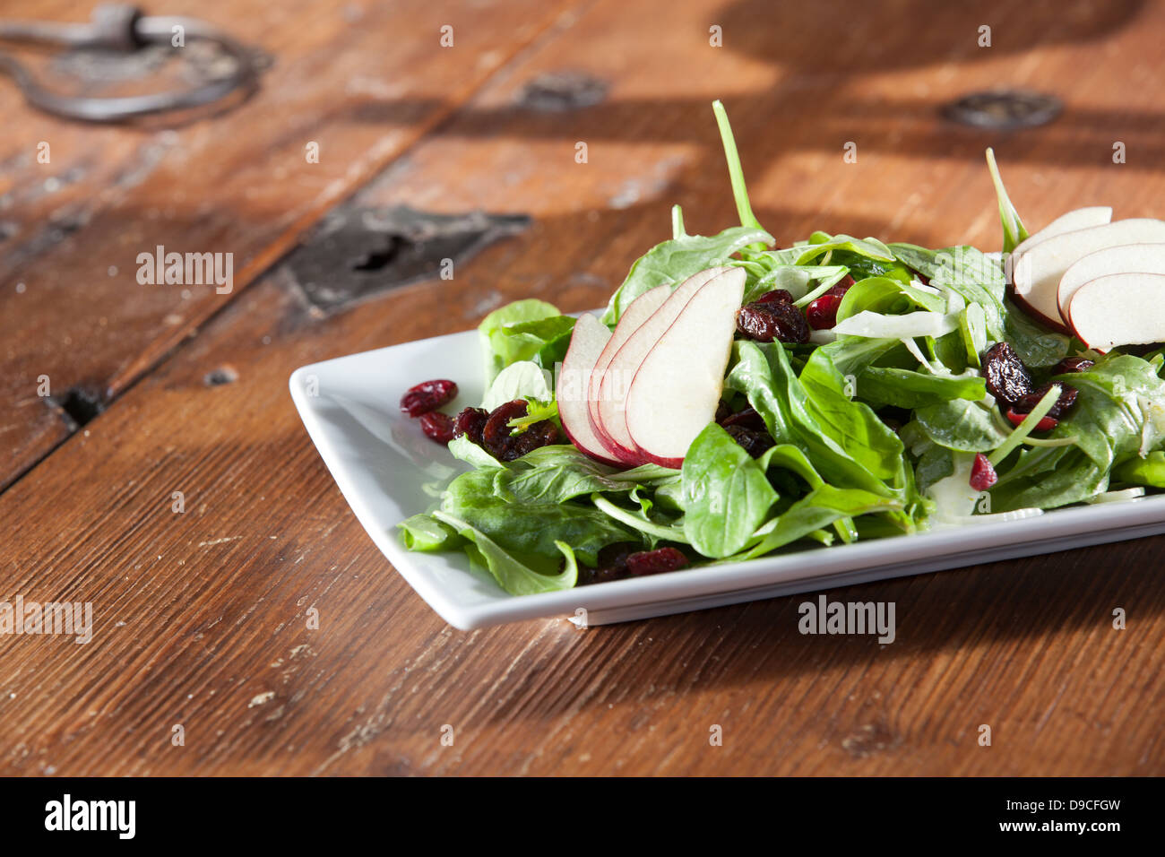 Gourmet artisan spinach, cranberry and pear salad sitting on a rustic wooden table in low light, ready to eat. Stock Photo