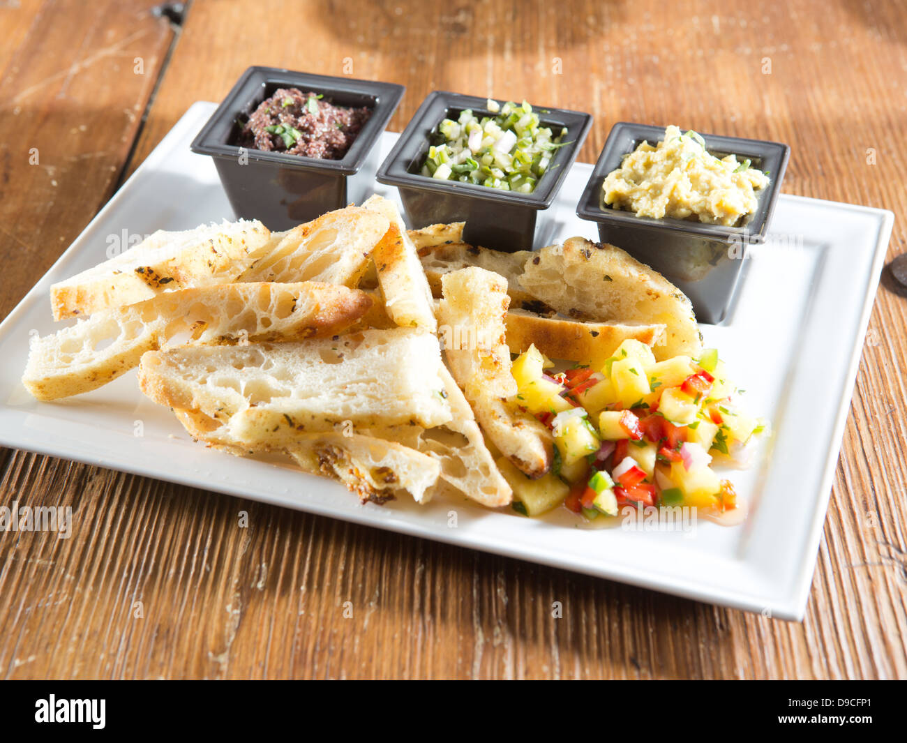 Large appetizer tray of toasted and sliced flaky artisan bread with pineapple mango salsa with