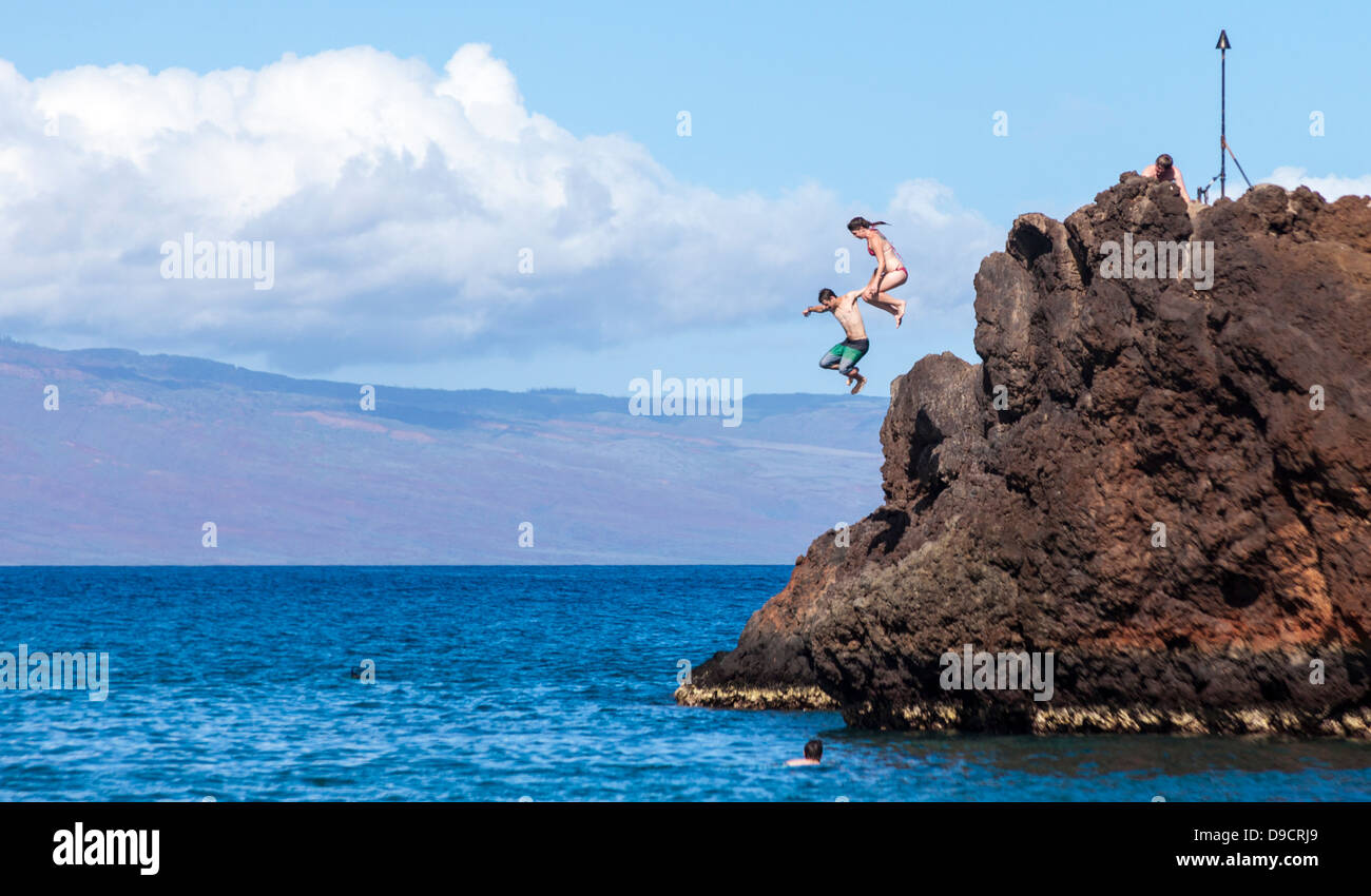 Adventurers jump off Black Rock at Kaanapali Beach, Maui Stock Photo