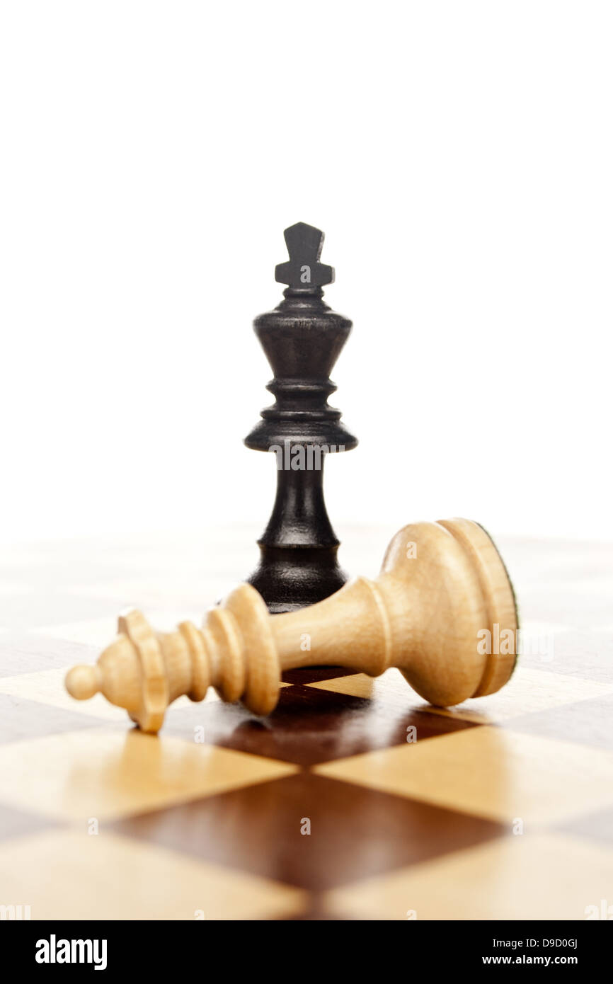 Chess pieces on a chess board, the black king and hit lady. Chess pieces on a chessboard, the black king and battered woman. Stock Photo