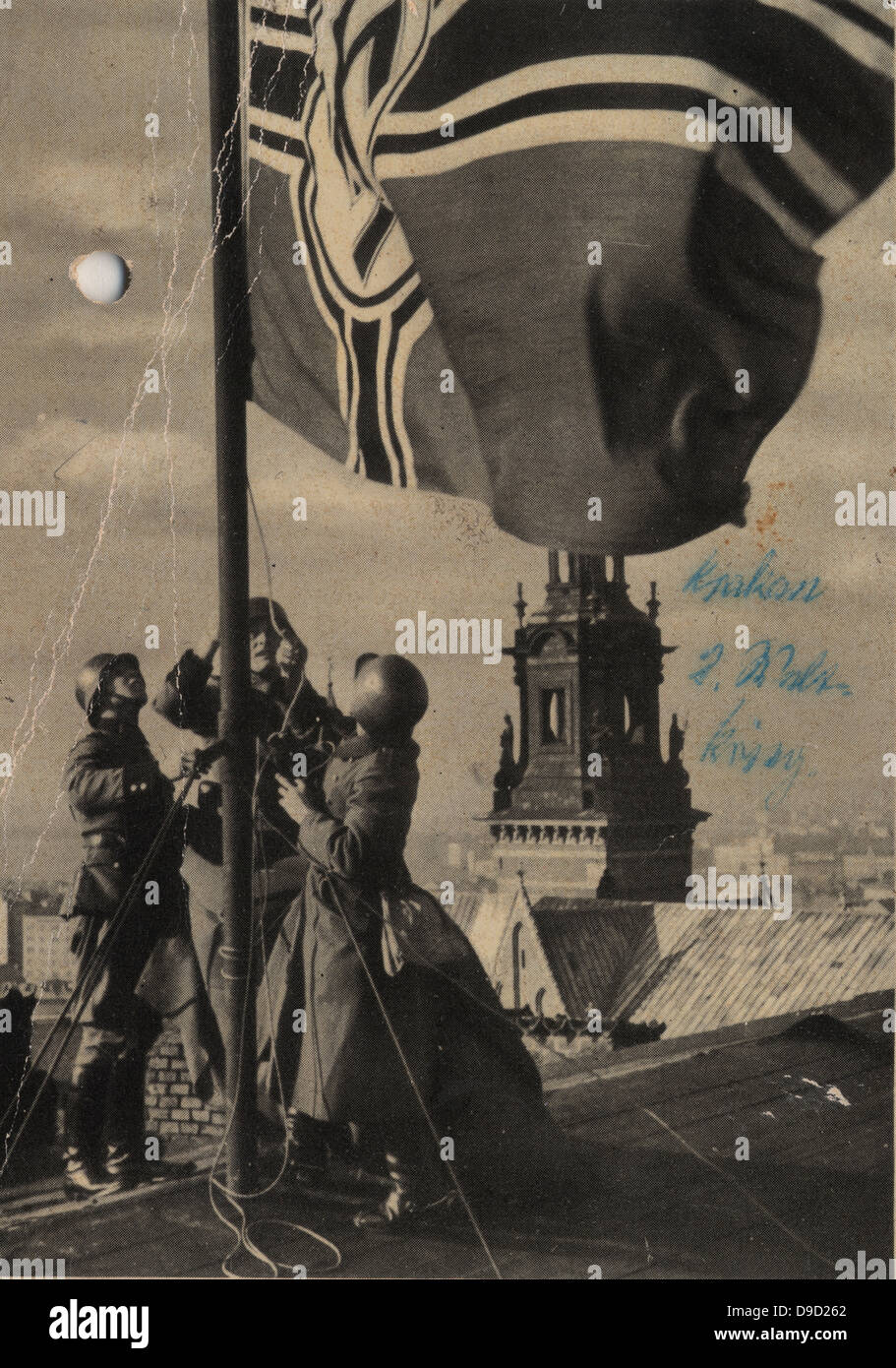 German troops hoising the Nazi flag in Cracow (Krakow), Poland, 1939. Official German postcard, World War II. Stock Photo