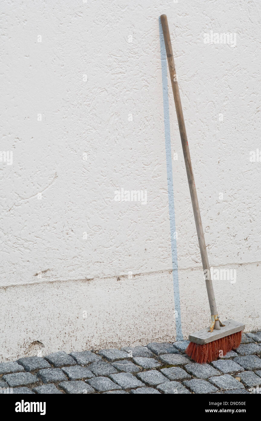 Simple red broom leaning on wall hires stock photography and images