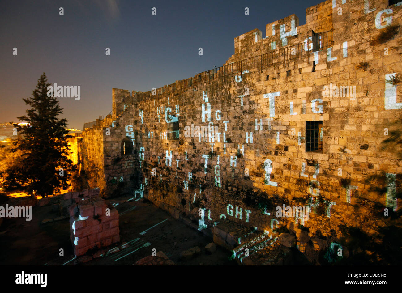 light show depicting the word Light in English projected over old city walls in Hatkuma garden during the Jerusalem Festival of Light in Israel which takes place annually around the old city with special effects illuminating historical sites and displays the work of leading international artists. Stock Photo