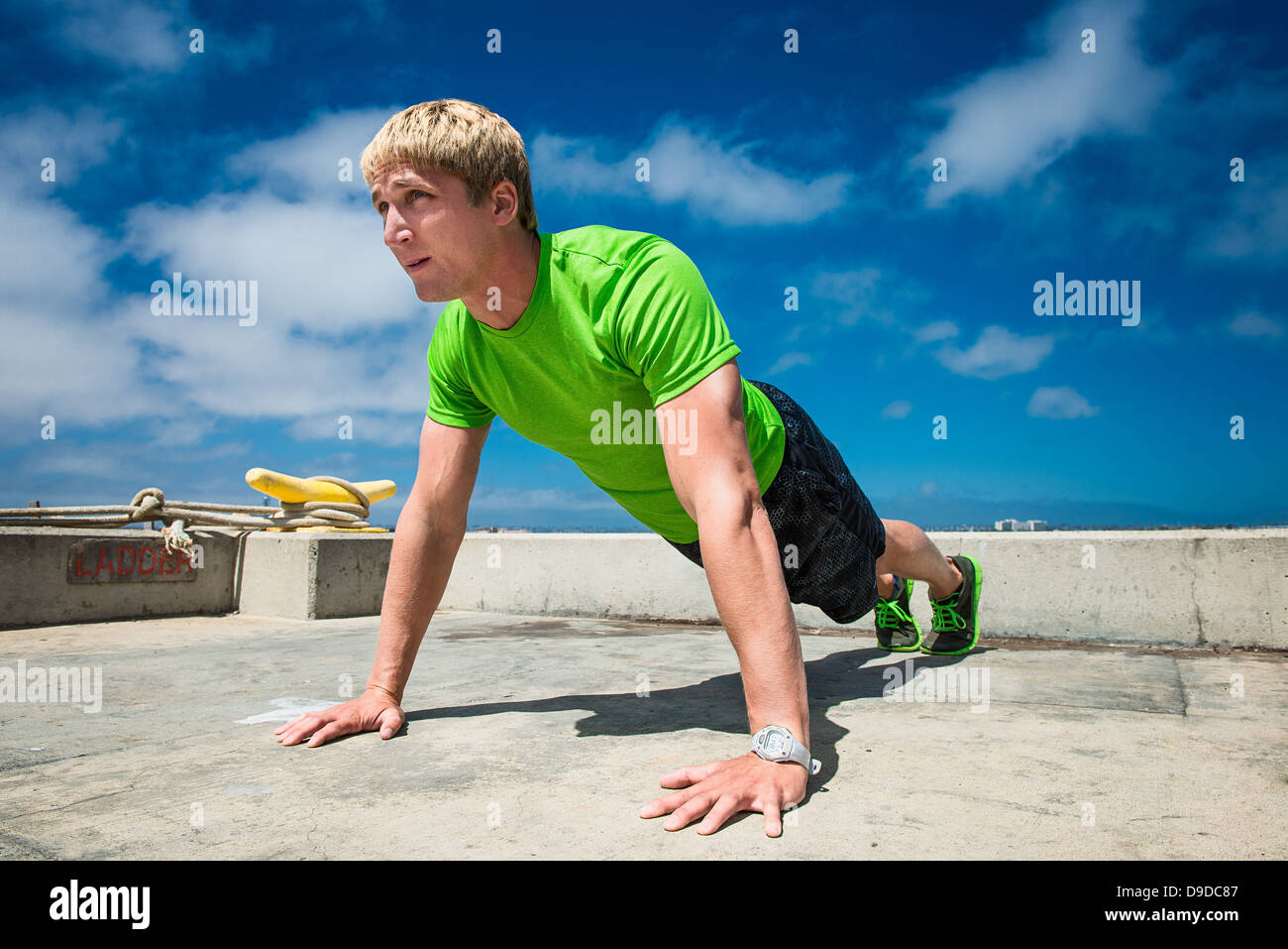 Young man performing push ups on pier Stock Photo