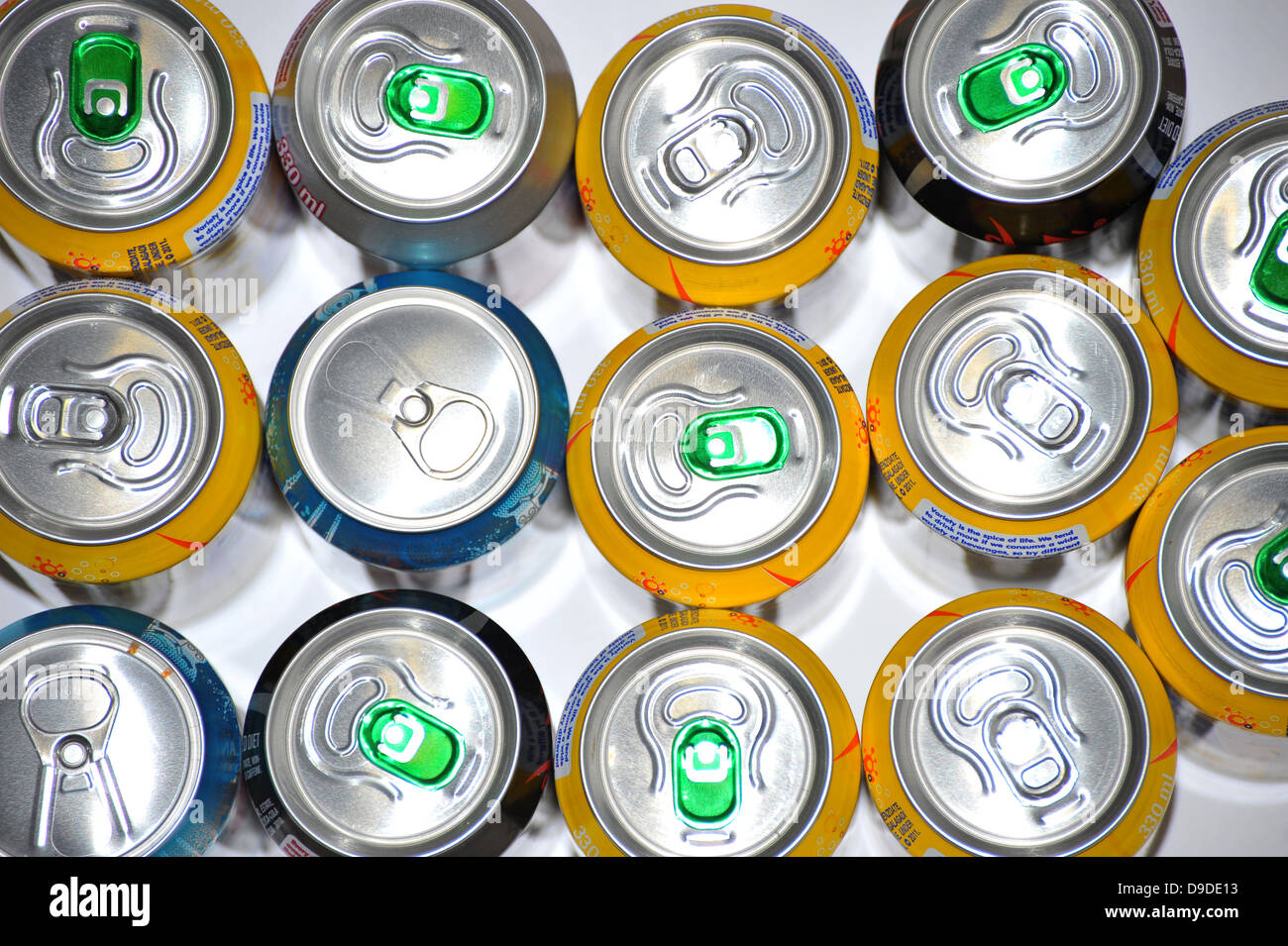The tops of a variety of cans of fizzy pop photographed against a white