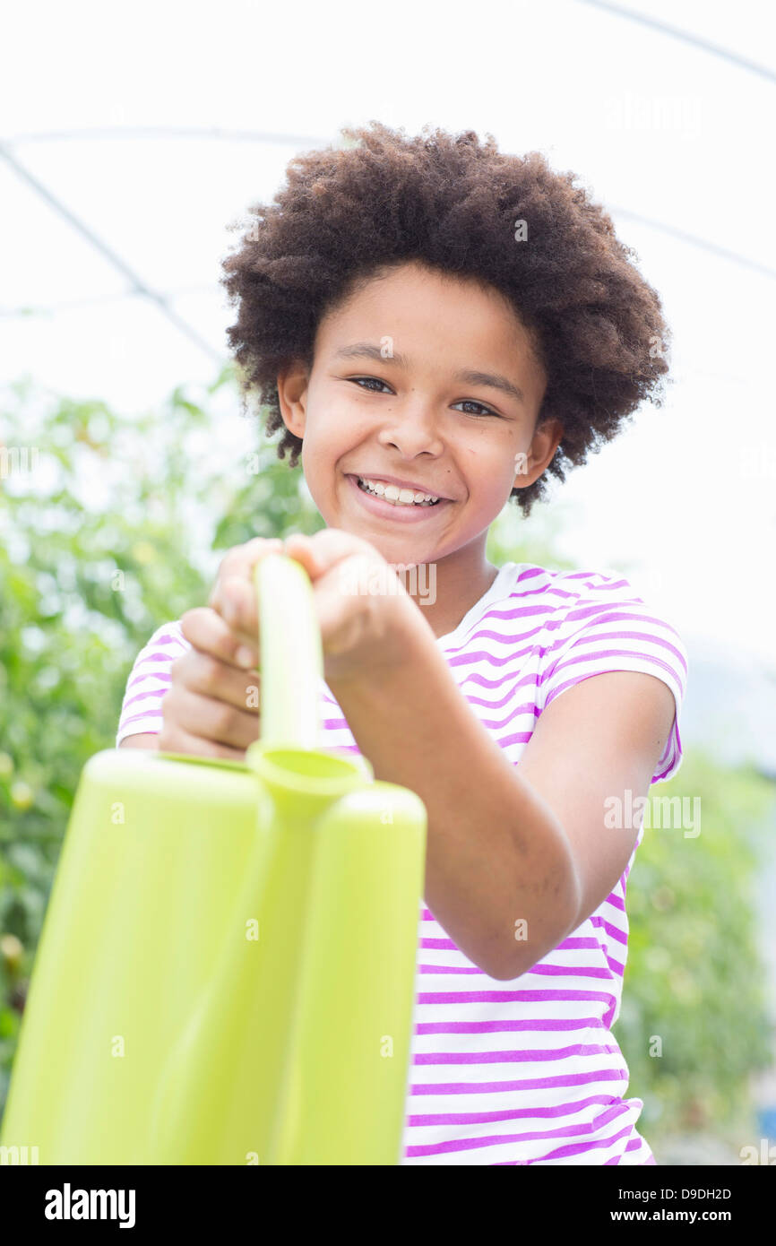 Girl holding green watering can Stock Photo