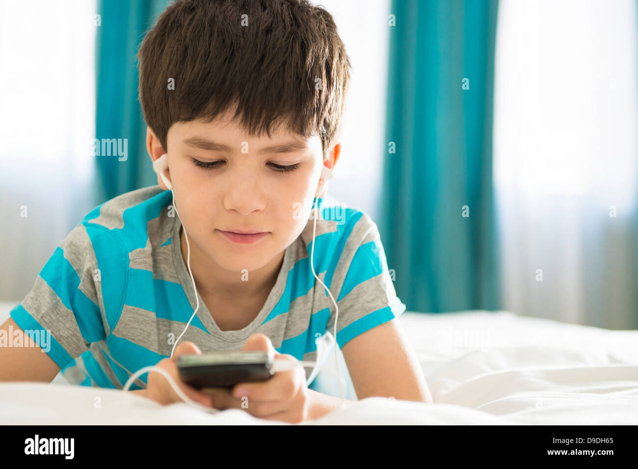Boy listening to mp3 player on bed Stock Photo
