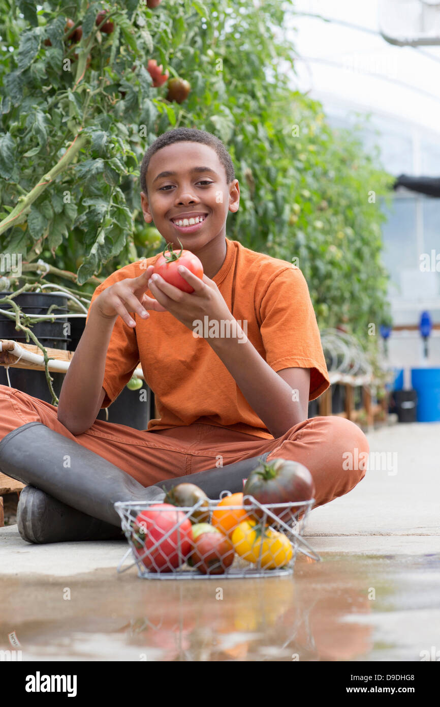 Boy sitting cross legged holding ripe tomato Stock Photo