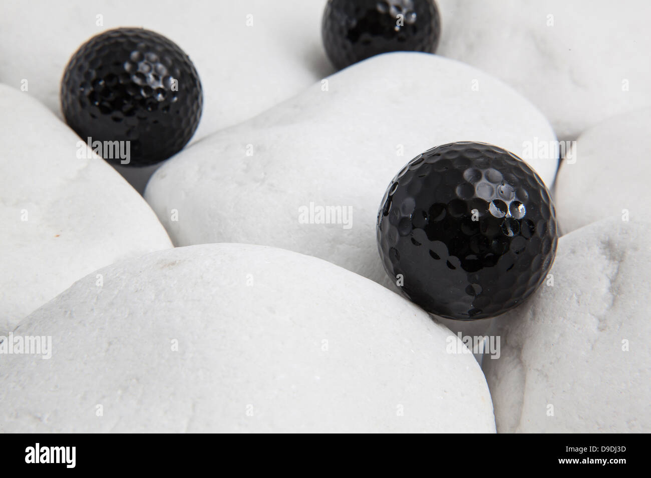 Three black golf balls on the white stones Stock Photo