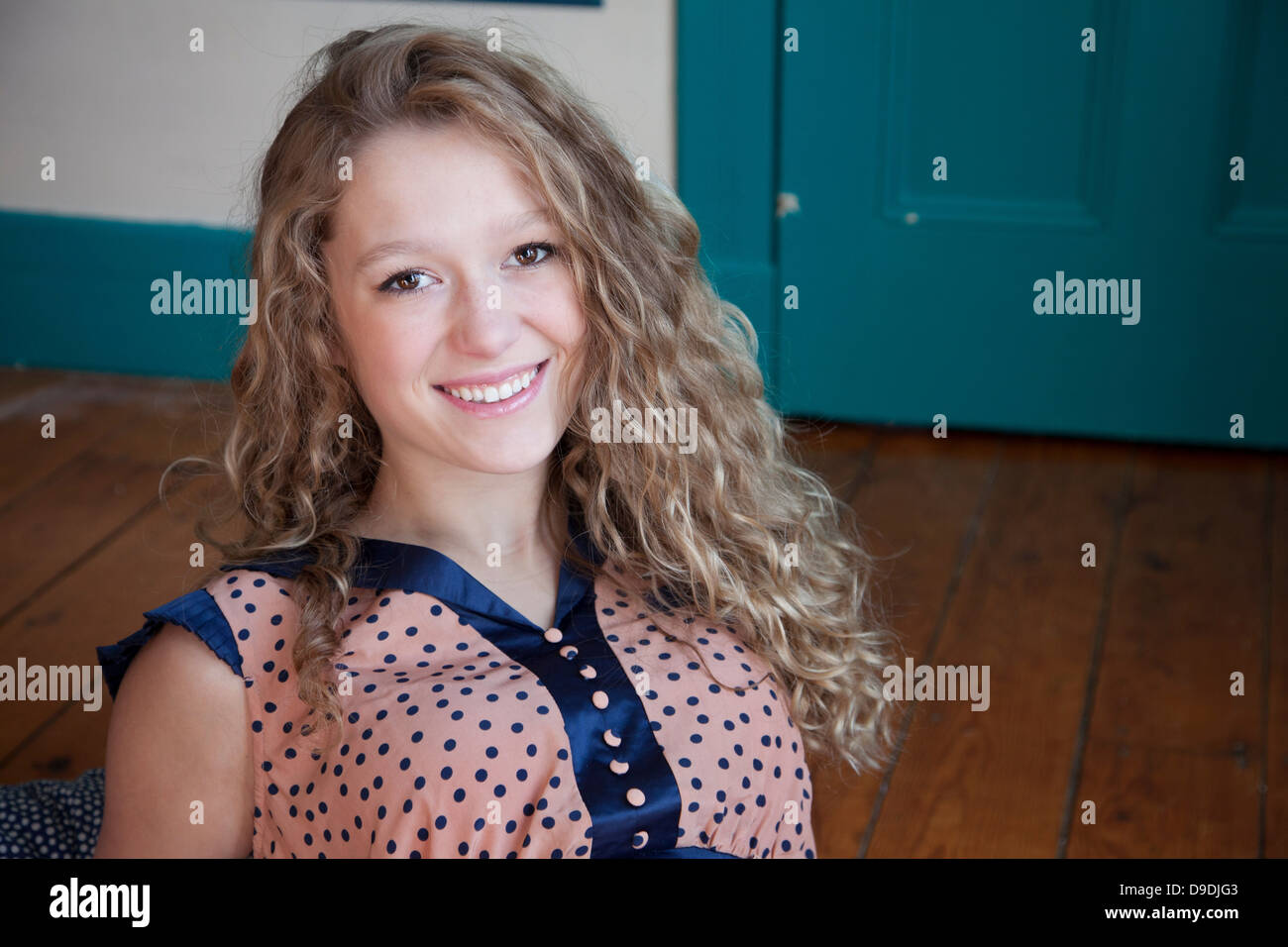 Teenager sitting in room with wooden floor Stock Photo