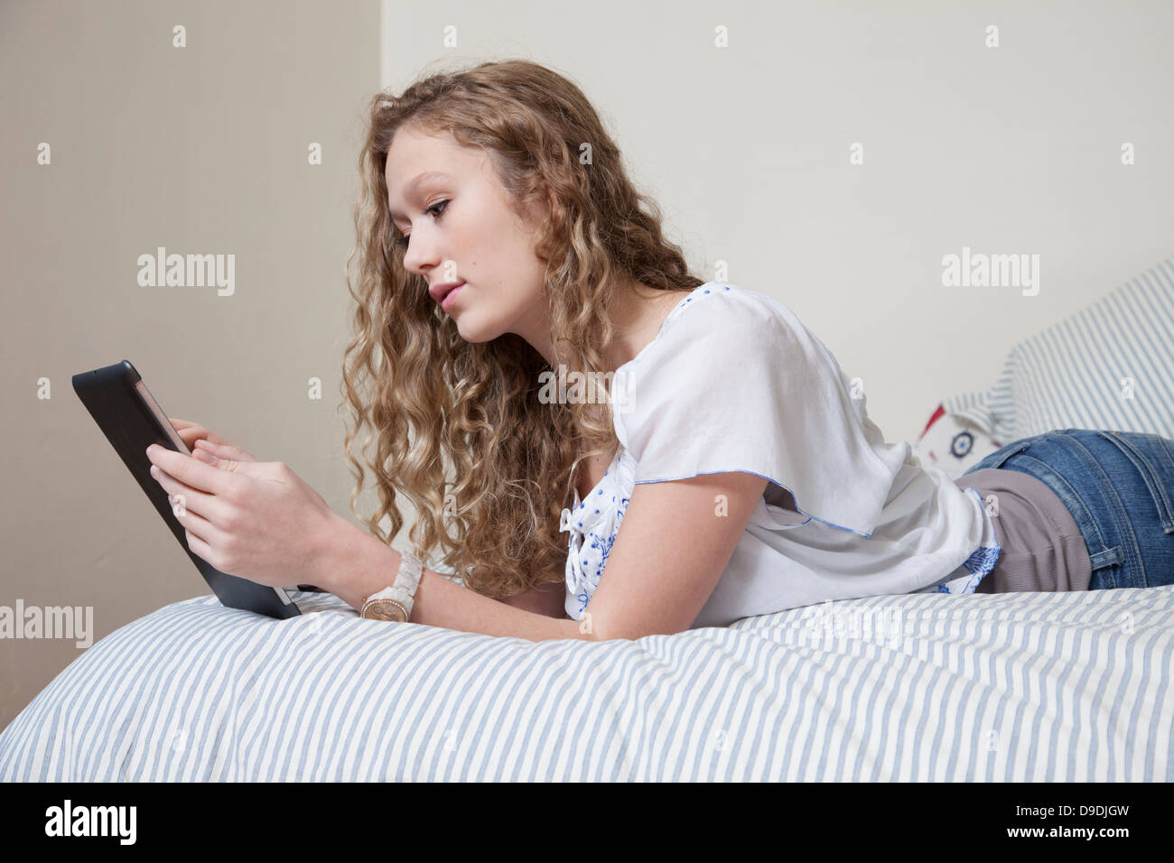 Teenager on bed, reading digital tablet Stock Photo