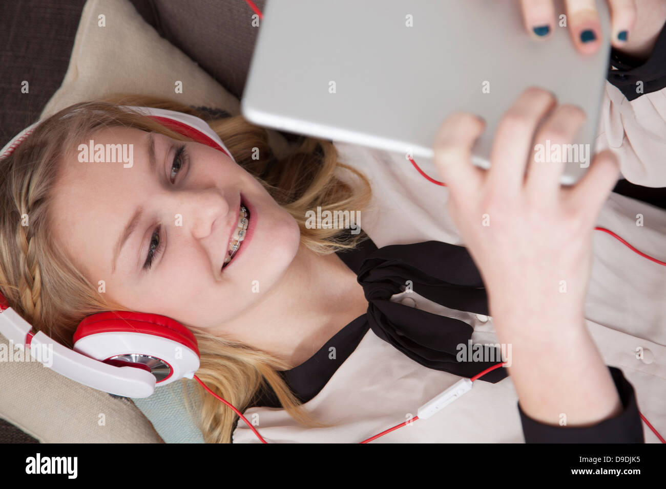 Girls lying on sofa using digital tablet Stock Photo