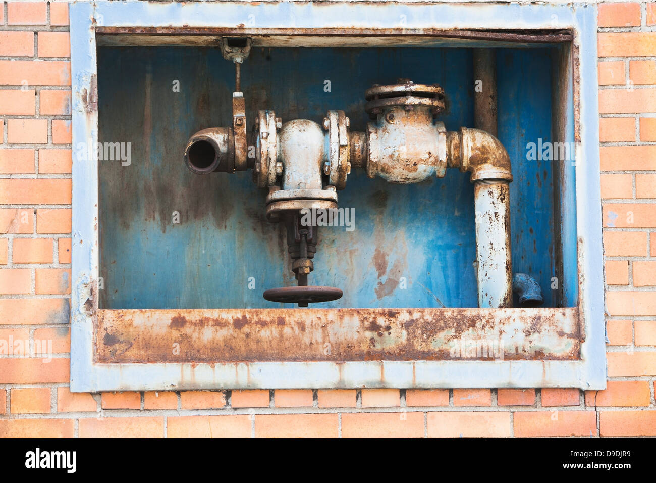 Rusting pipes inside red brick wall Stock Photo