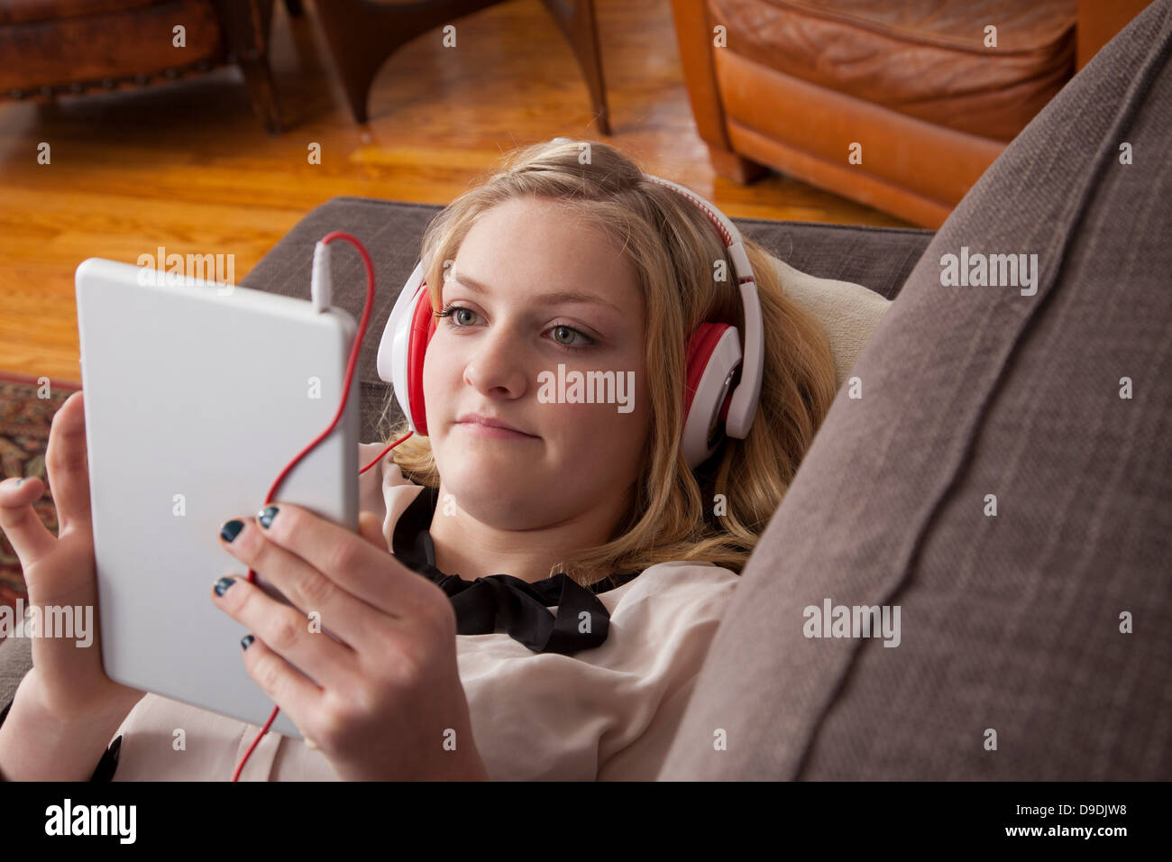 Girl lying on sofa using digital tablet Stock Photo