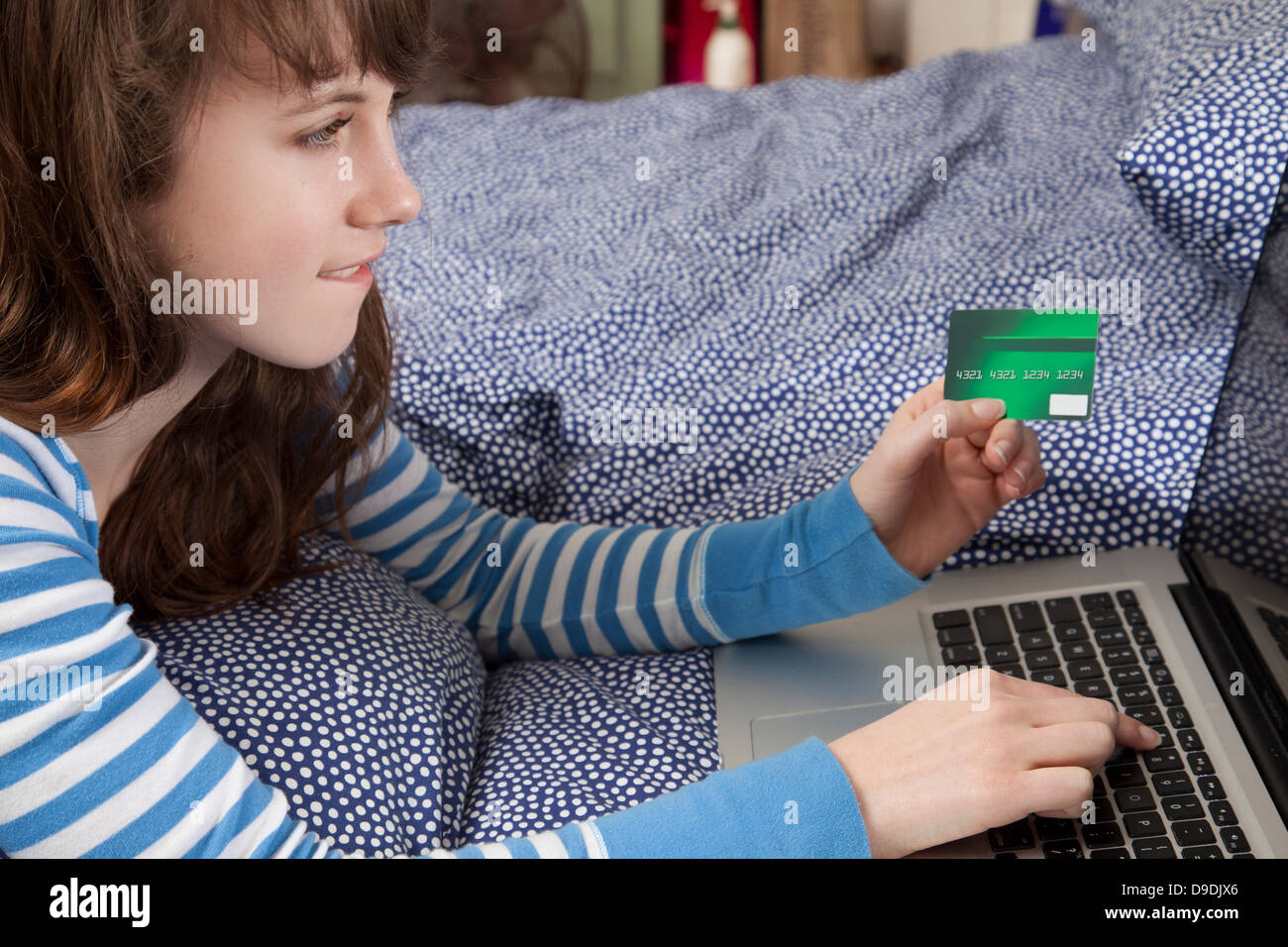 Girl lying on bed with laptop internet shopping Stock Photo