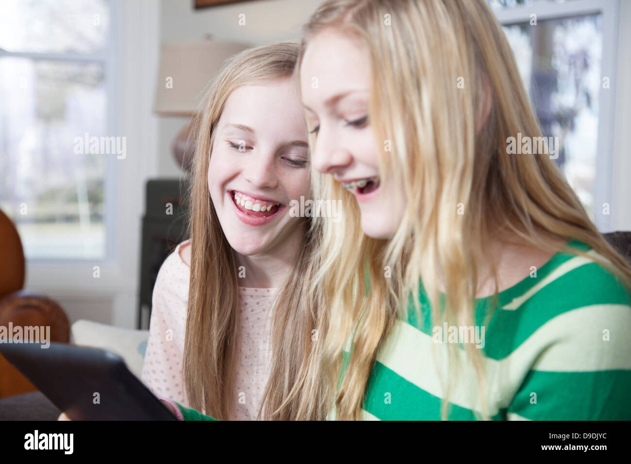 Girls sitting on sofa looking at digital tablet Stock Photo