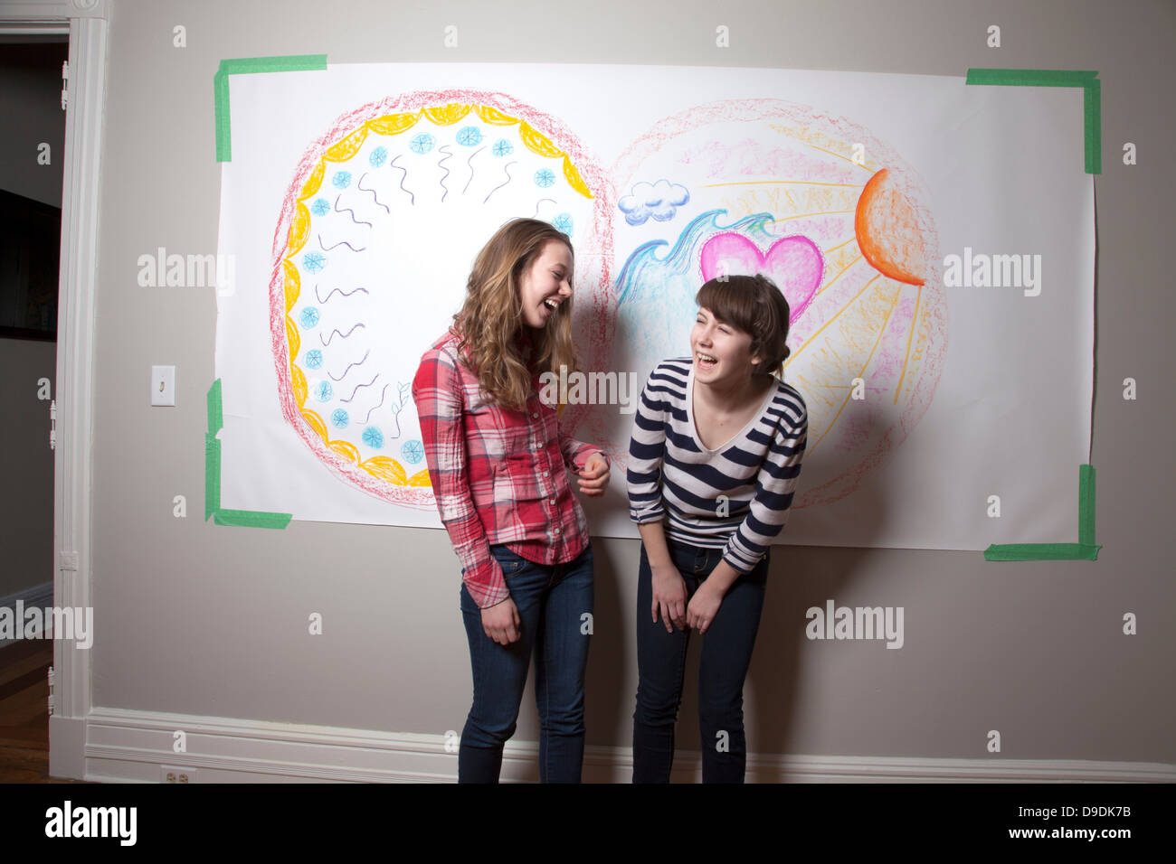 Girls standing in front of mural laughing Stock Photo