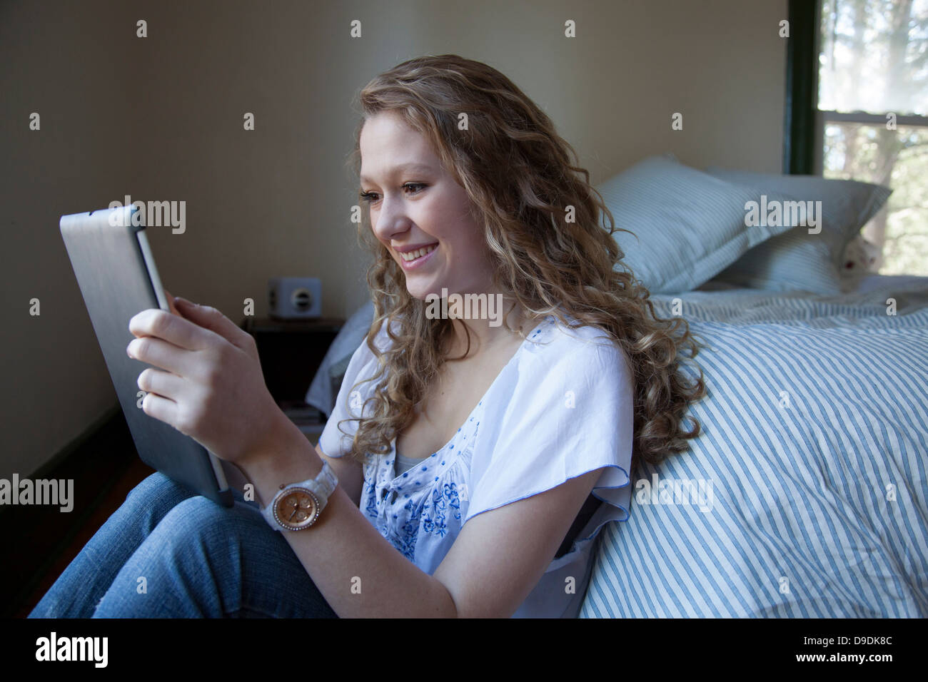 Teenager on bed, reading digital tablet Stock Photo