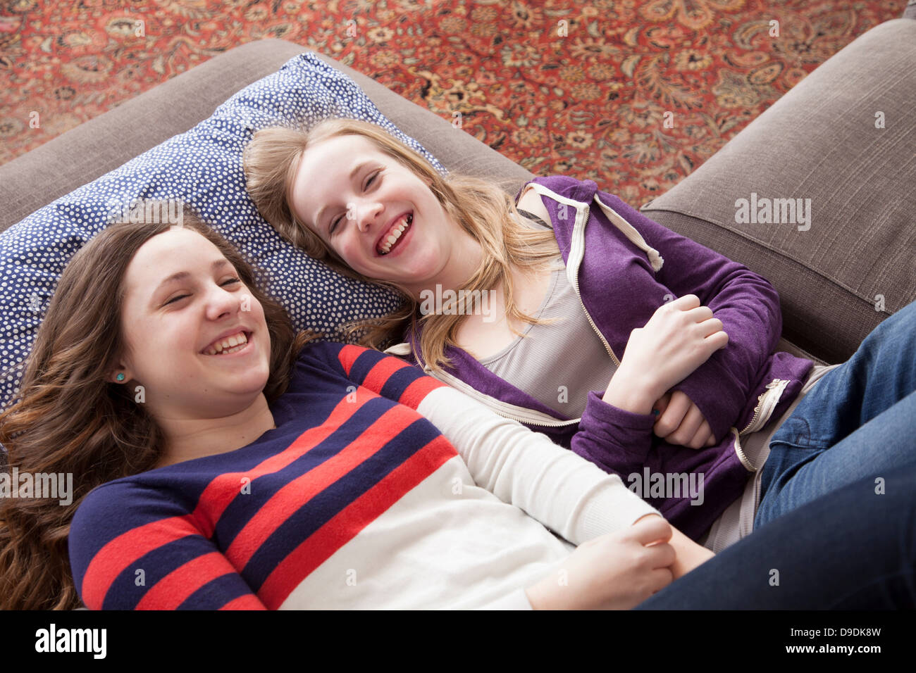 Girls lying on sofa giggling Stock Photo
