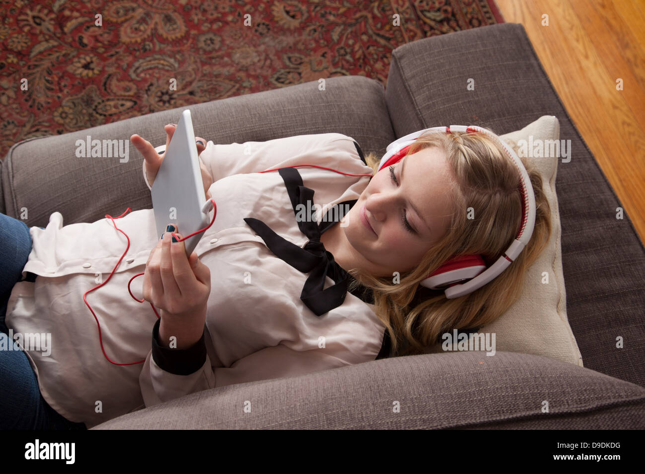 Girls lying on sofa using digital tablet Stock Photo