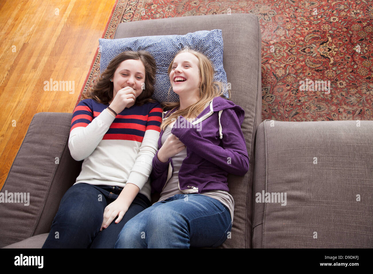 Girls lying on sofa giggling Stock Photo