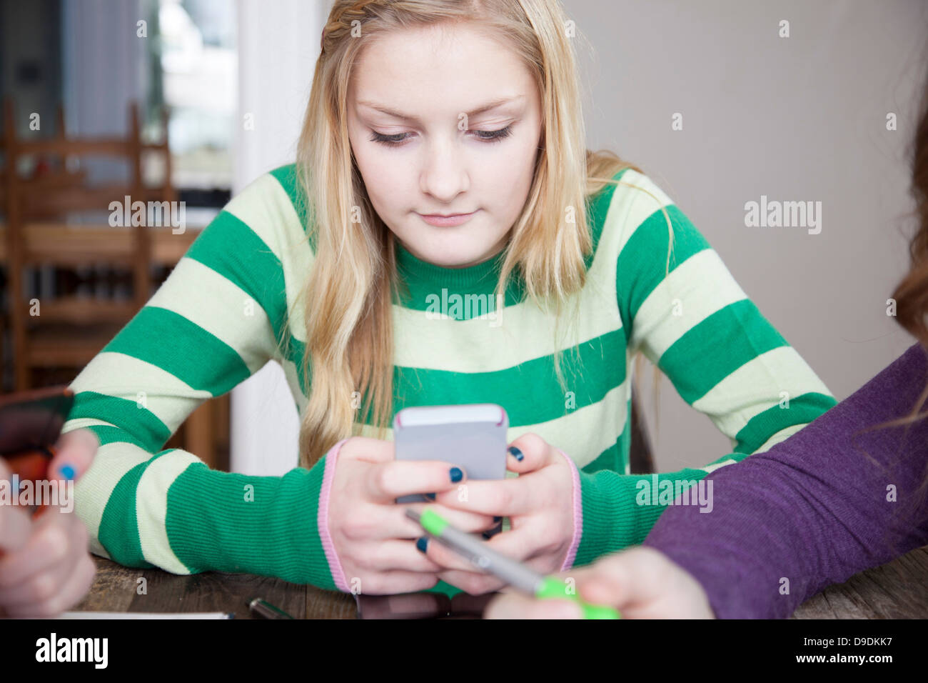 Girls sitting at table using smart phone Stock Photo