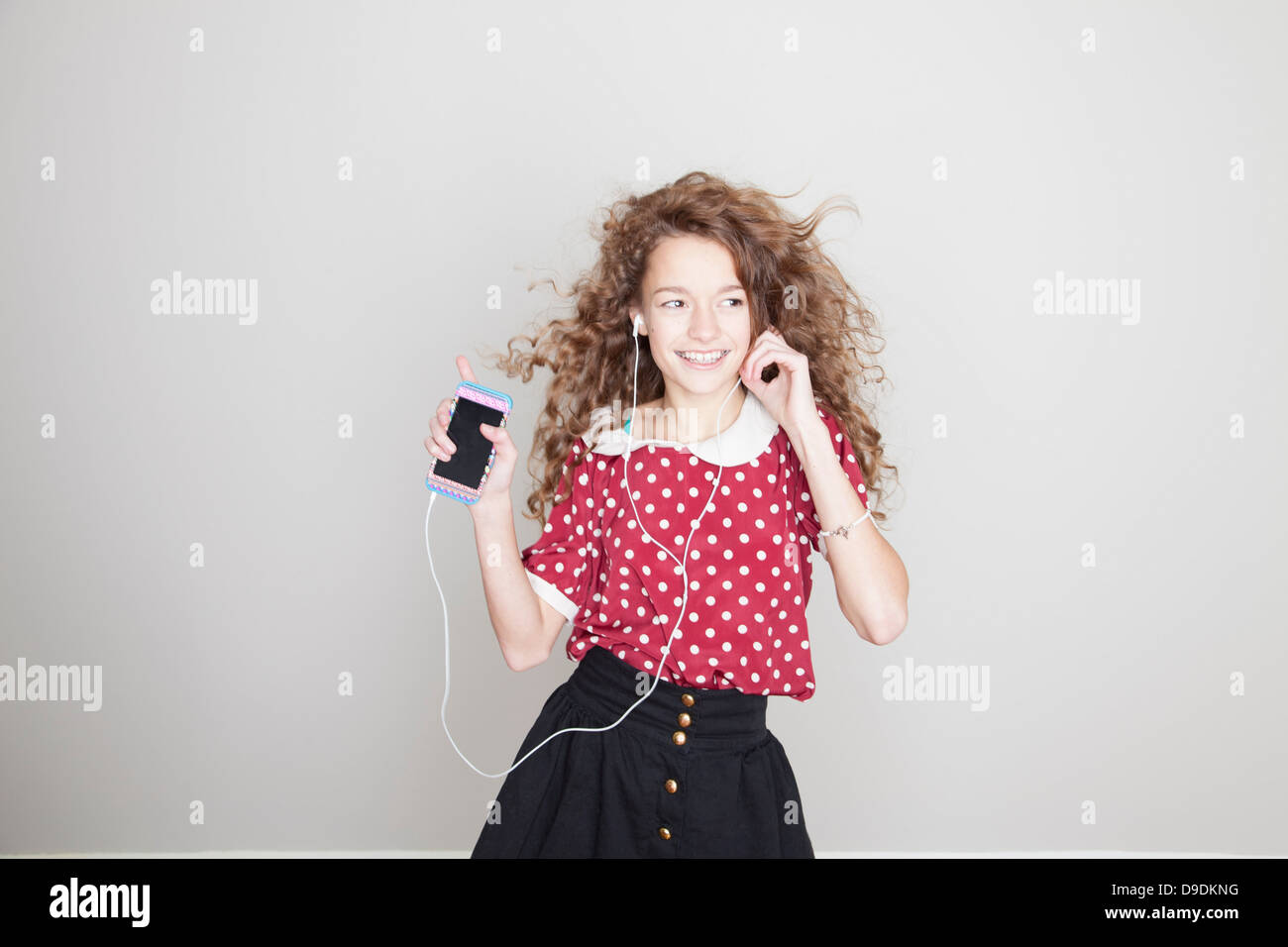 Girl wearing headphones, dancing and holding mp3 player Stock Photo