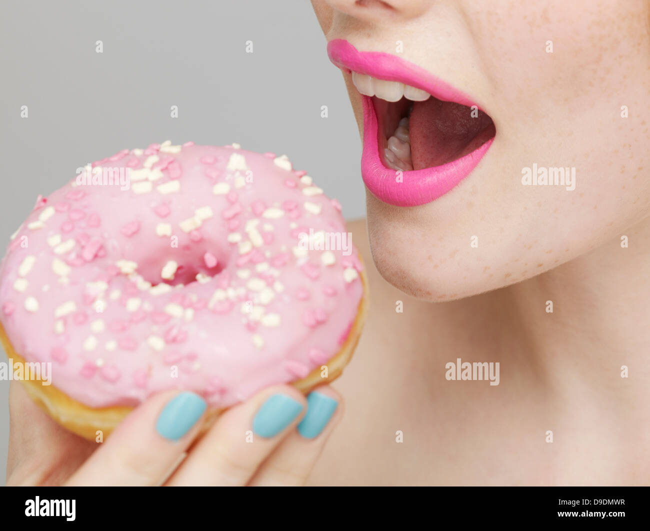 Woman wearing pink lipstick eating doughnut Stock Photo