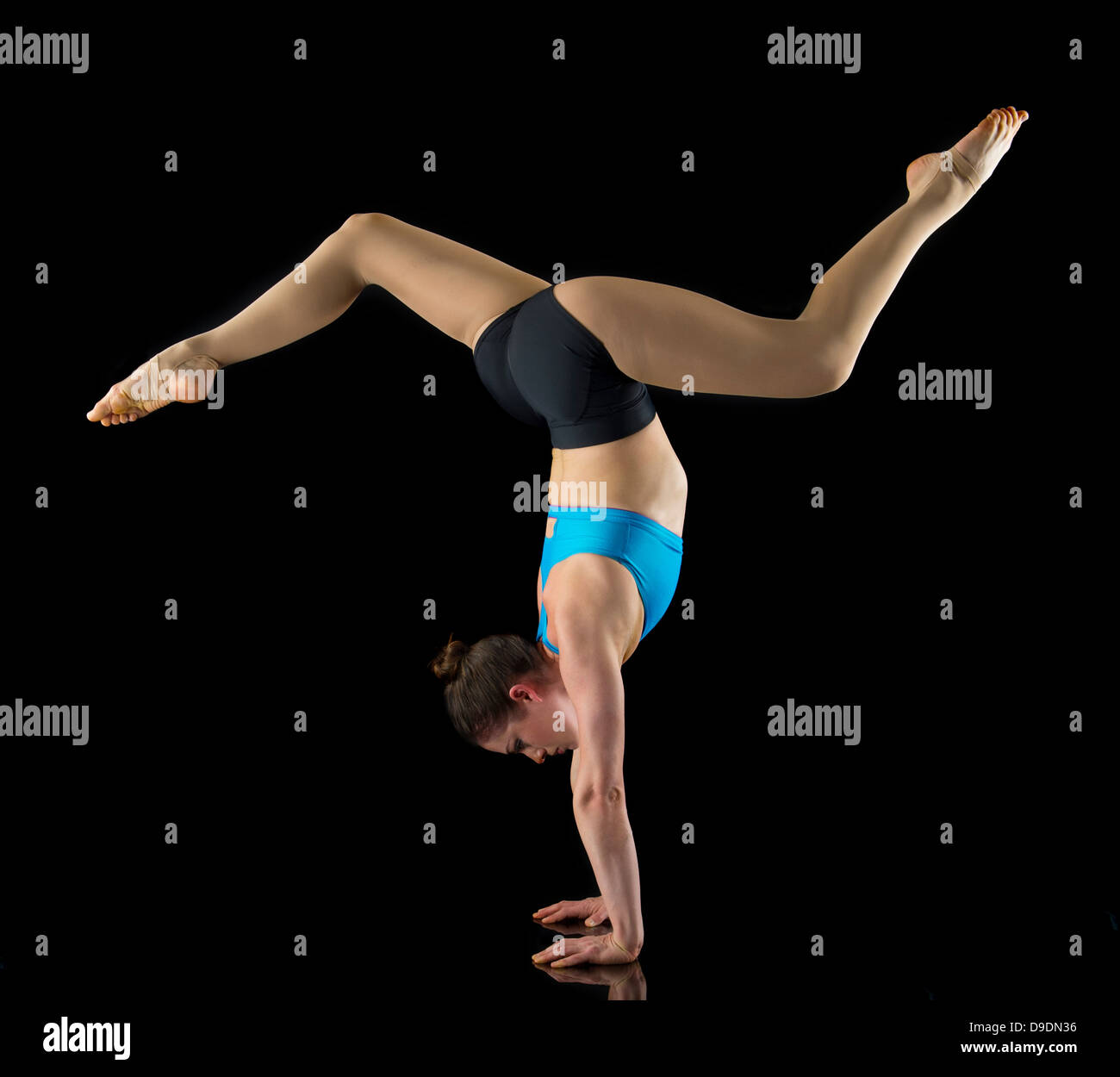 Acrobat performing handstand in front of black background Stock Photo