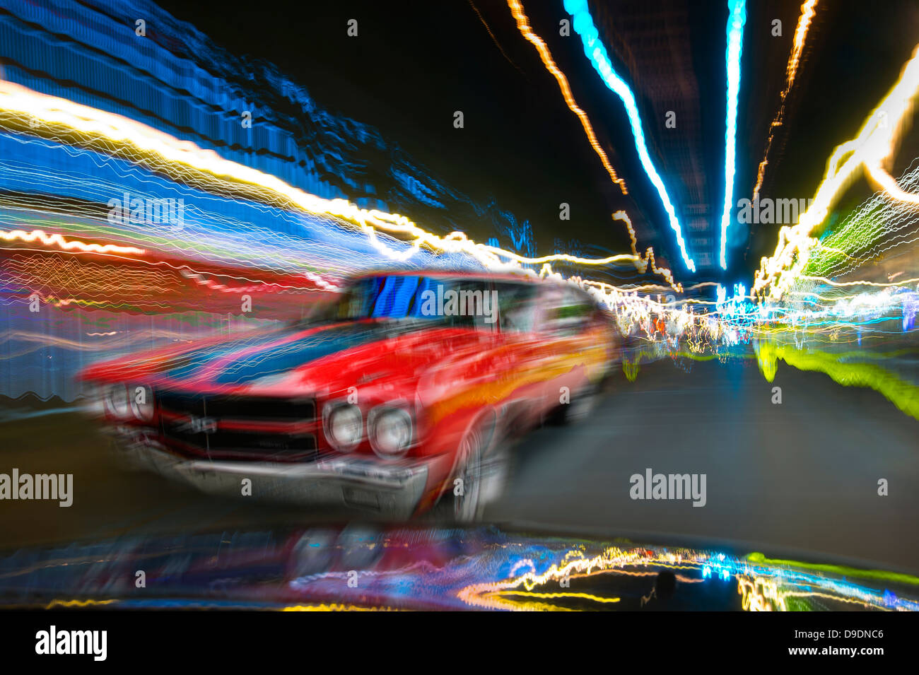 Red Car Moving Through Town At Night Stock Photo