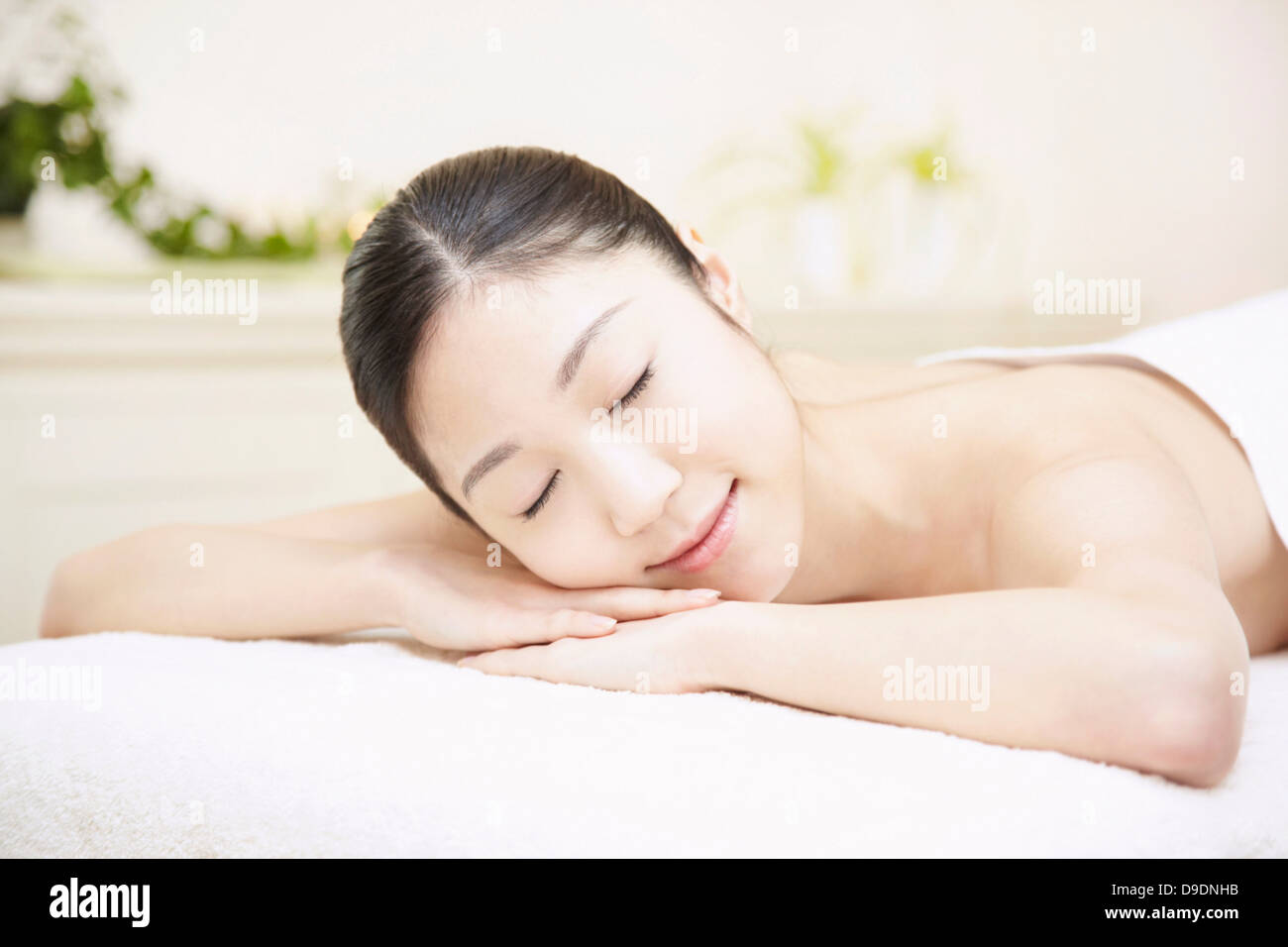 Woman lying on front in spa, eyes closed Stock Photo