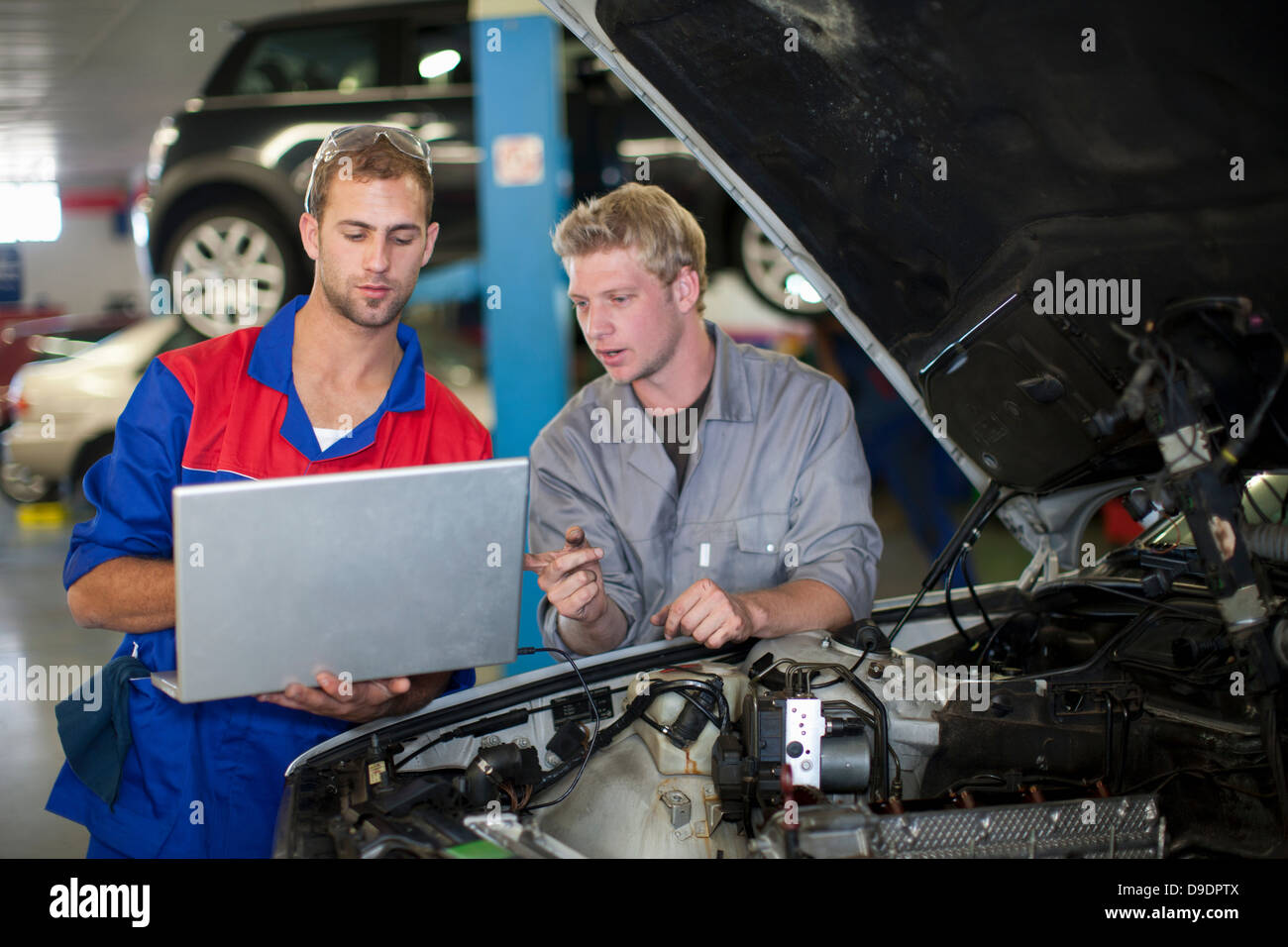Car mechanics discussing and analyzing car repair Stock Photo - Car Mechanics Discussing AnD Analyzing Car Repair D9DPTX