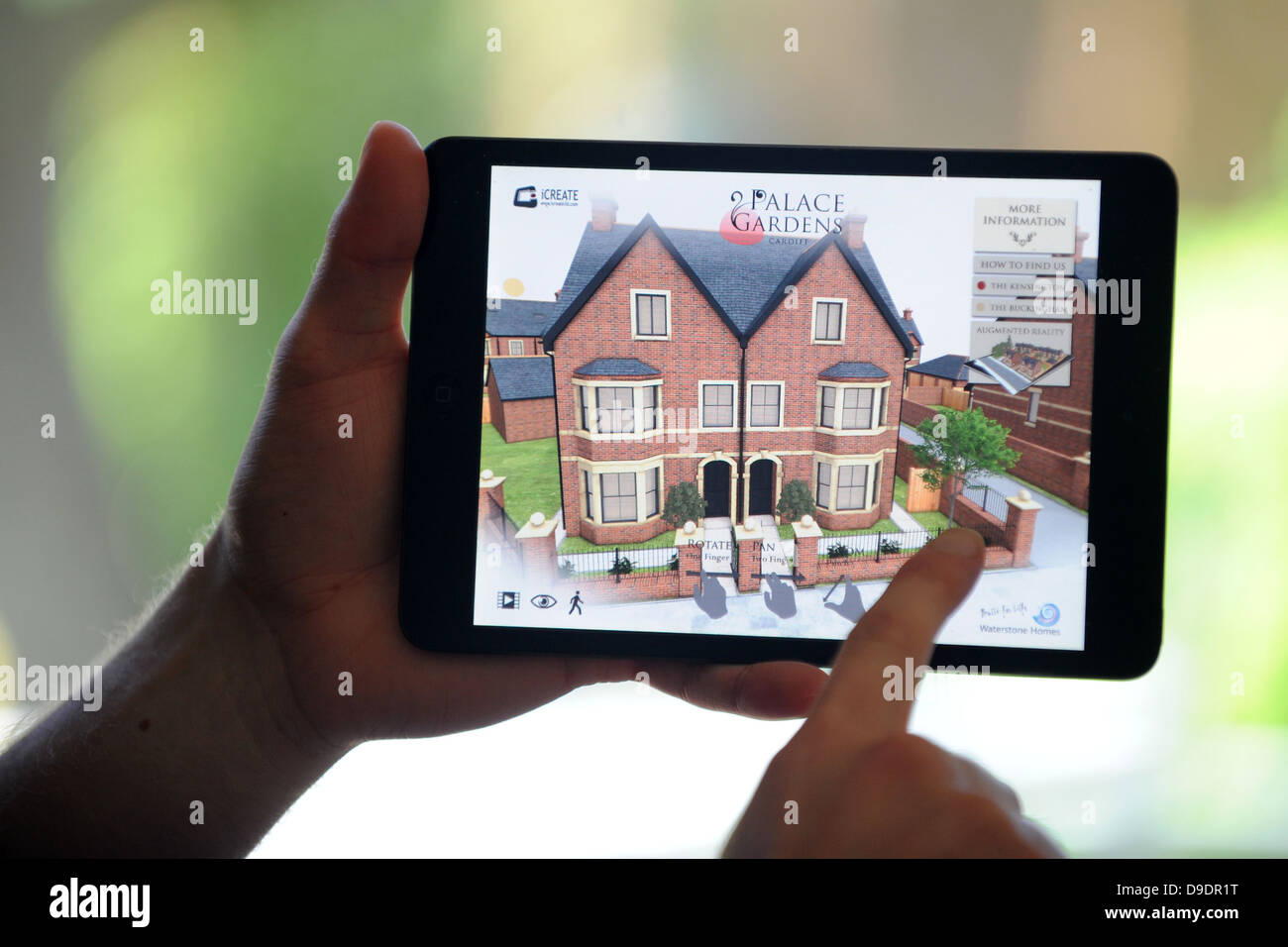 Hands on an ipad tablet showing a 3d virtual tour of a new home. Stock Photo