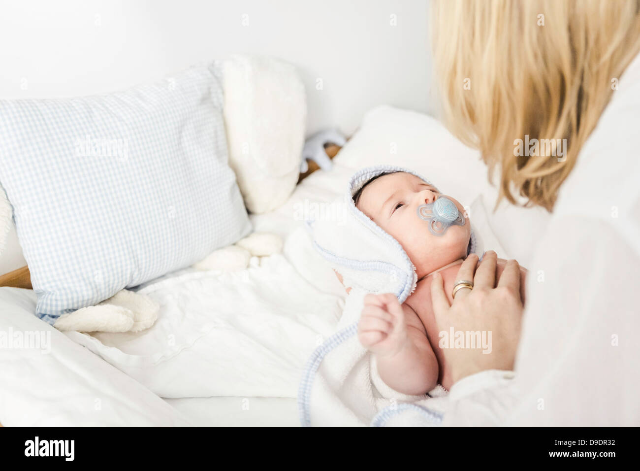 Mid adult mother putting baby boy in cot Stock Photo Alamy
