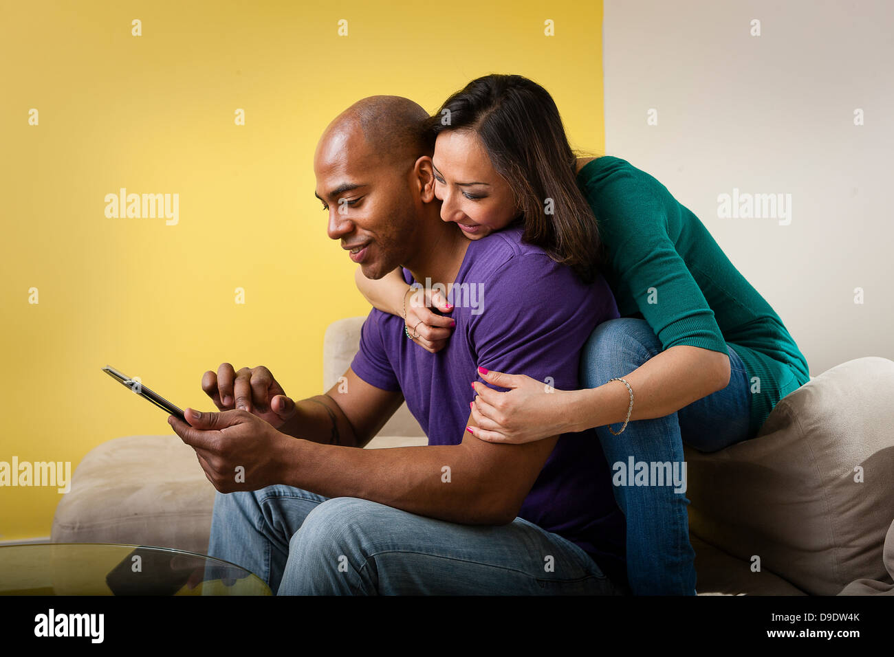 Mid adult couple sitting on sofa looking at digital tablet Stock Photo