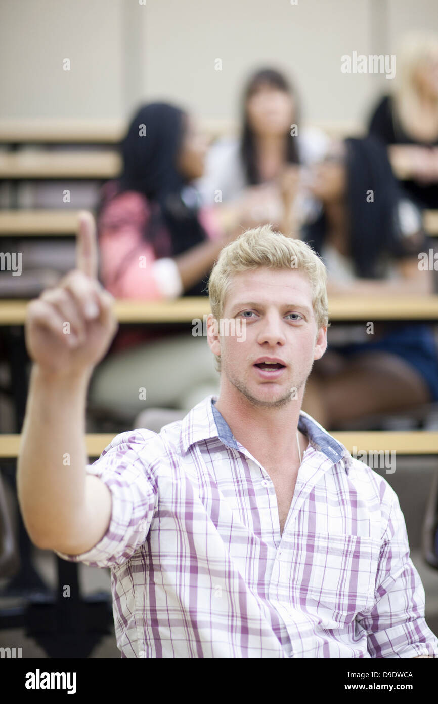 Male student in lecture with arm raised Stock Photo