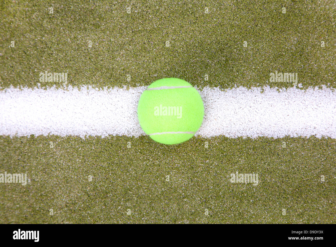 Yellow tennis ball on the white line seen from above. Stock Photo