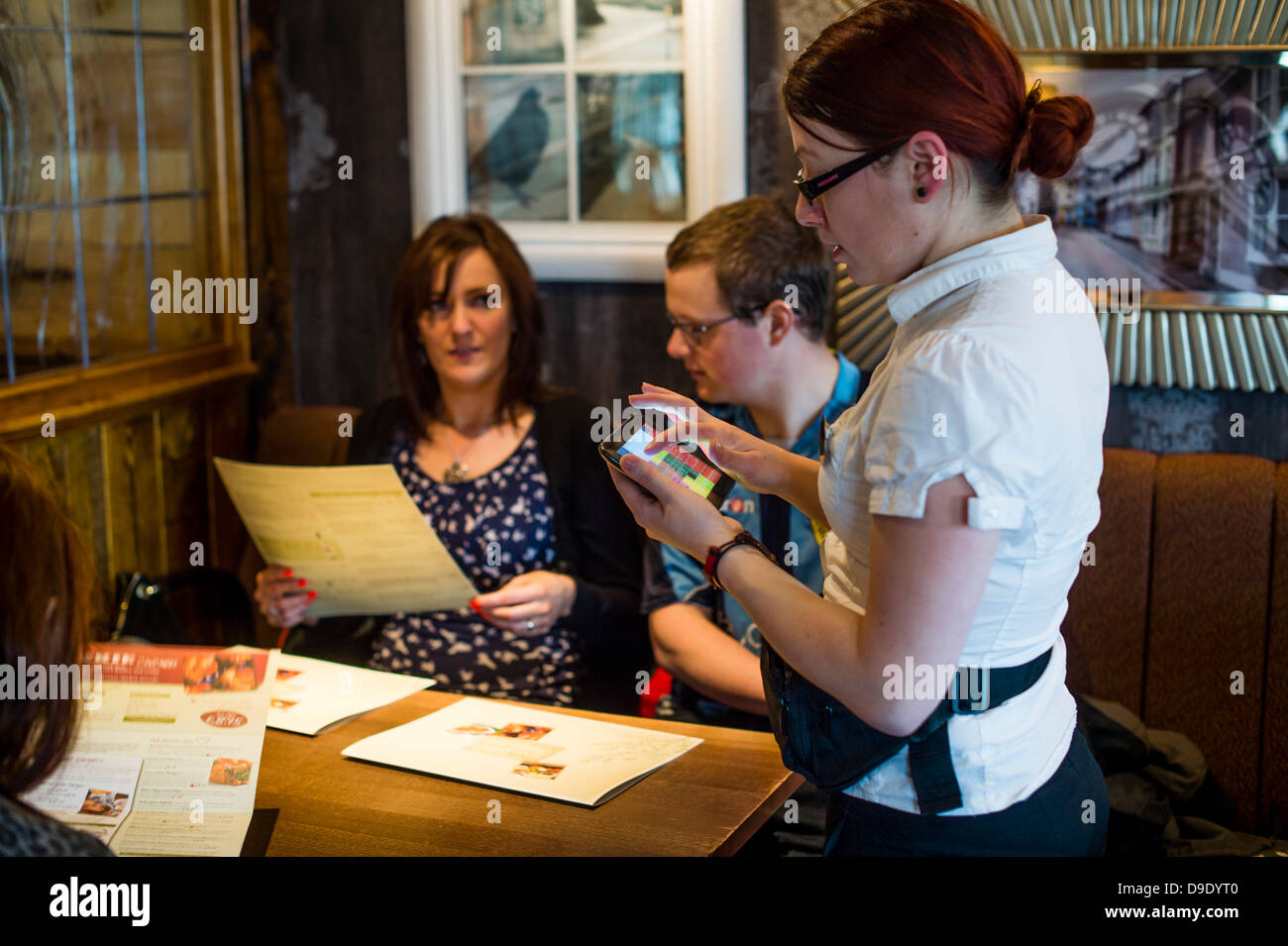 A waitress taking an order for food in a restaurant pub using a