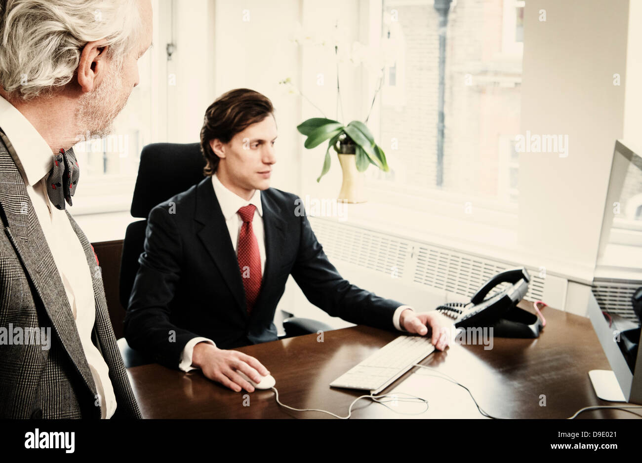 Young businessman at desk with senior man in office Stock Photo