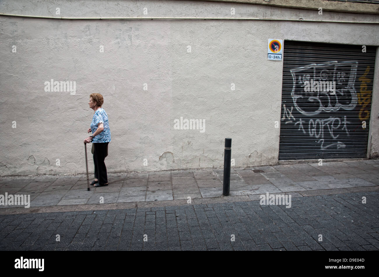 Woman with crutch walking by the streets of Gracia neighborhood