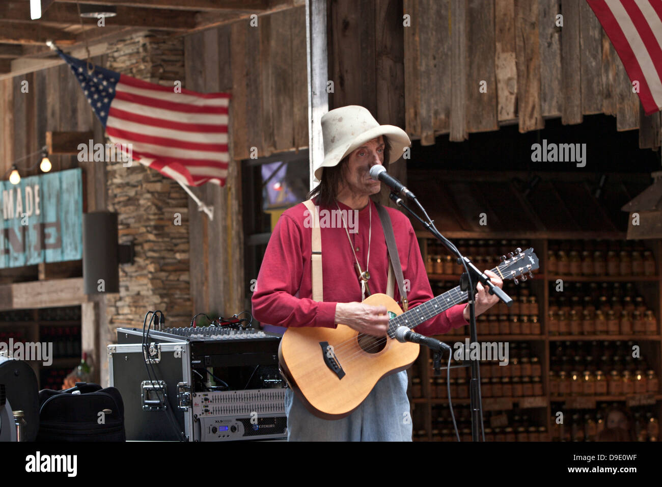 Country music performer singing with guitar on stage in shopping mall