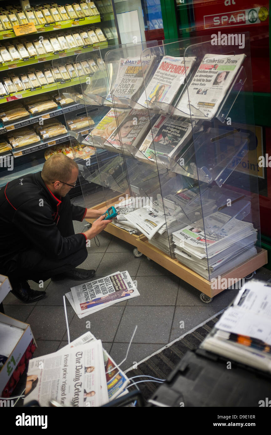 A early delivery of daily UK newspapers being scanned before going on sale at a branch of Spar convenience store UK Stock Photo