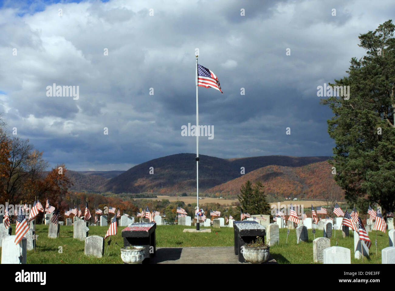 GRAVE HIGHLAND CEMETERY, SOLDIERS CIRCLE, VETERANS OF ALL WARS, AMERICAN FLAGS. MOUNTAINS, TREES, AND STORM CLOUDS IN BACKGROUND Stock Photo