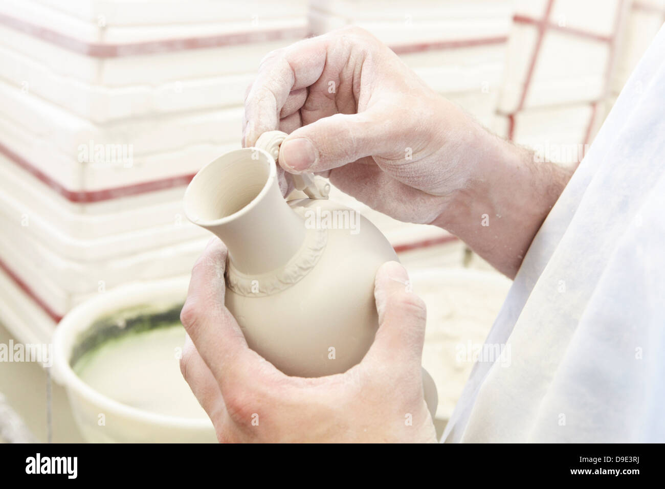 Man attaching handle to jug in pottery factory Stock Photo