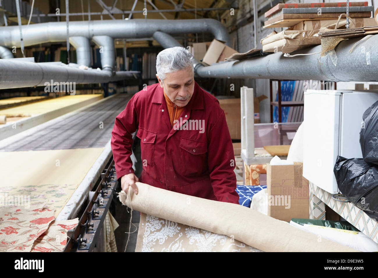 Man holding roll of fabric in textiles factory Stock Photo