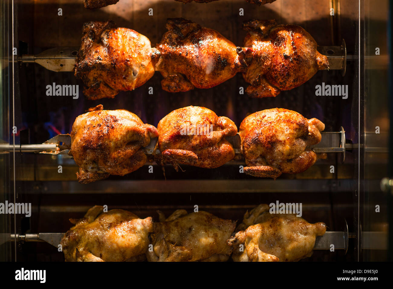 Roast chickens cooking in a rotisserie in a pub cafe restaurant UK